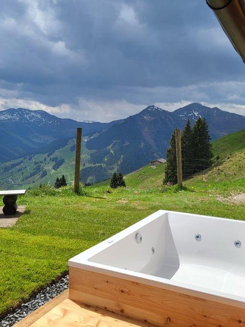 An outdoor hot tub with a view of the mountains in summer.