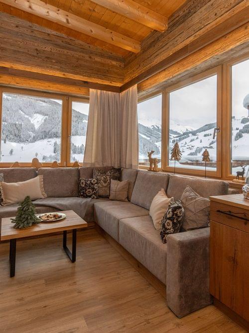 Gemütliches Chalet-Wohnzimmer mit Panoramablick auf verschneite Berge
