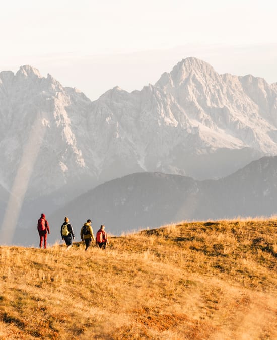 Four hikers walking along a mountain ridge, with an autumnal atmosphere.