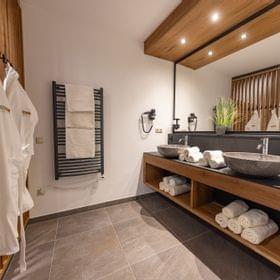 Modernes Spa-Badezimmer mit Steinausguss, gerollten Handtüchern und Holzakzenten