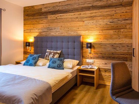 Cozy hotel room with double bed, wood panel wall, reading lights and modern decor