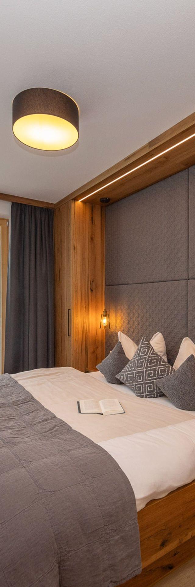 Cozy hotel bedroom with wooden furnishings, mountain view, and modern lighting