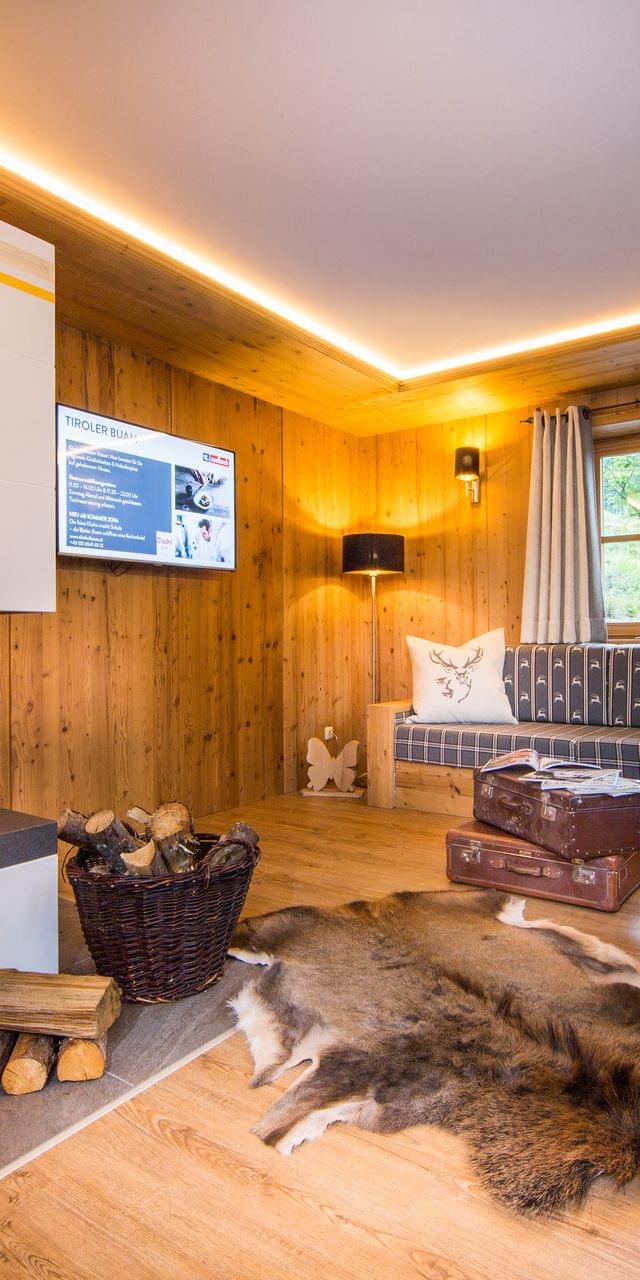 A cozy living room with a seating area and a fireplace, in an alpine-chic style with lots of wood.