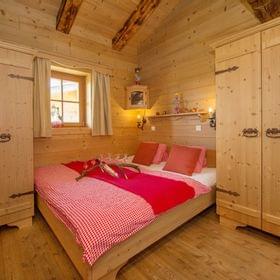 Cozy alpine bedroom with wooden walls, red checkered bedding and rustic furniture