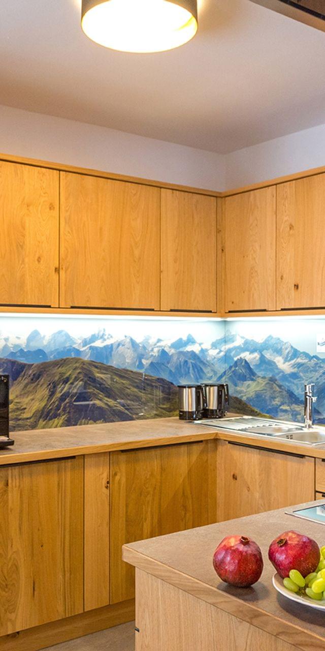 Moderne Holzküche mit Einbaugeräten und Rückwand mit Berglandschaft
