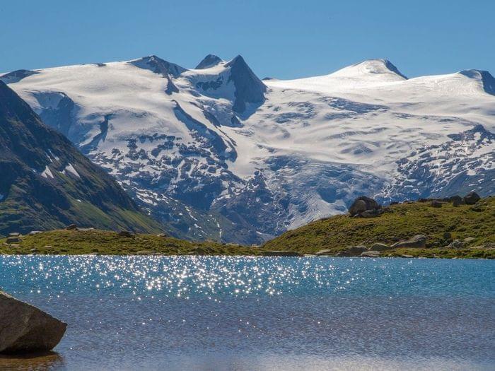 Schneebedeckte Alpen spiegeln sich in klarem blauen See an einem sonnigen Tag