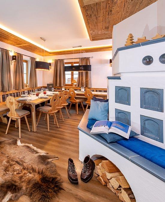 Gemütliches alpines Chalet-Esszimmer mit Holzmöbeln, Kachelofen und Fellteppich