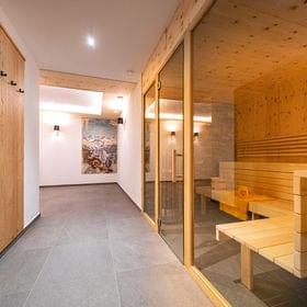 Modern wellness area with wooden sauna cabin and mountain photo on the wall