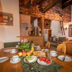 Rustikaler Alpen-Essbereich mit Holzbalken, gedecktem Frühstückstisch und gemütlicher Sitzecke