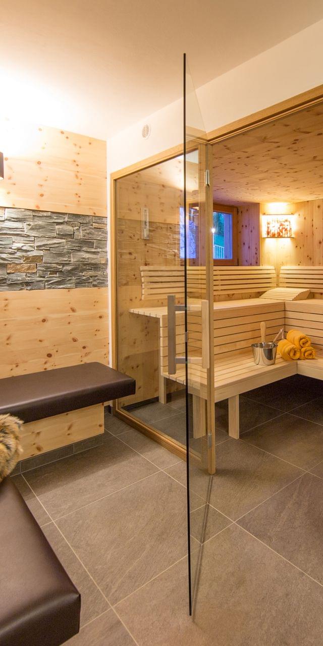 A large sauna with a glass front, with a cozy bench in front for relaxing.