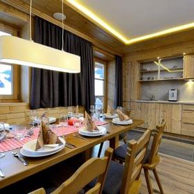 Rustic alpine kitchen and dining table set for dinner with wooden interior and mountain view