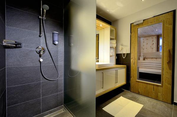 Modern bathroom with walk-in shower and wooden sauna cabin