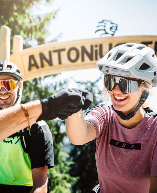 Mountain bikers smiling and fist bumping at the Antonius Trail entrance