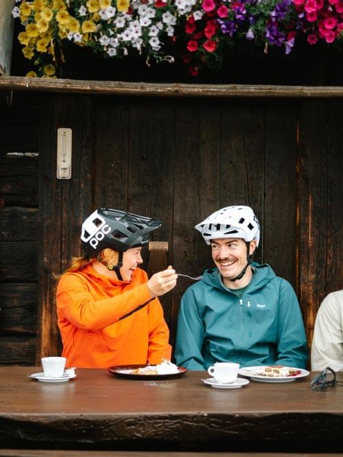 3 Mountainbiker auf deiner Bank bei einer Hütte 