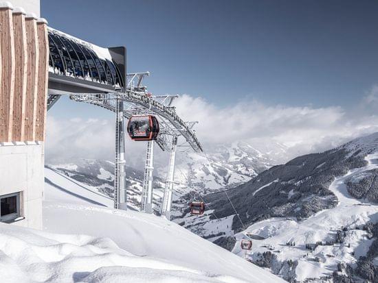 Modern ski gondola ascending snowy alpine slopes under blue sky in winter