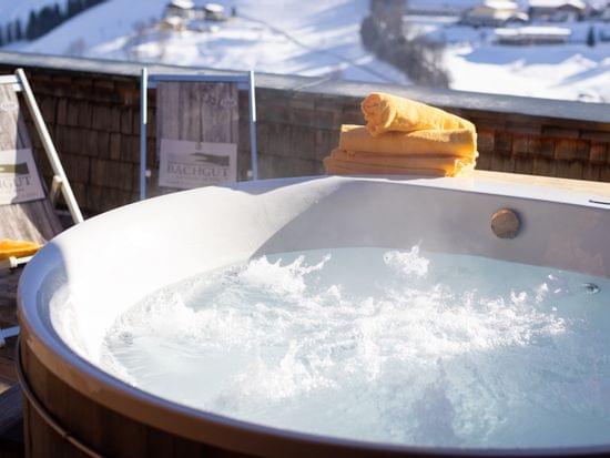 Blubbernde Whirlwanne auf der Terrasse mit Liegestühlen, im Hintergrund Winterlich Verschneite Landschaft 