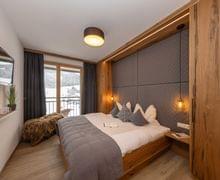 Gemütliches Hotelzimmer mit Holzmöbeln, Bergblick und moderner Beleuchtung