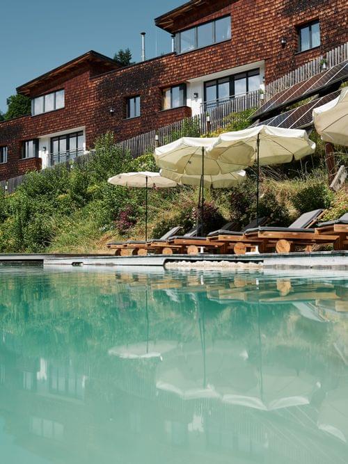 Anlage mit Schwimmteich und Chalets im Hintergrund 