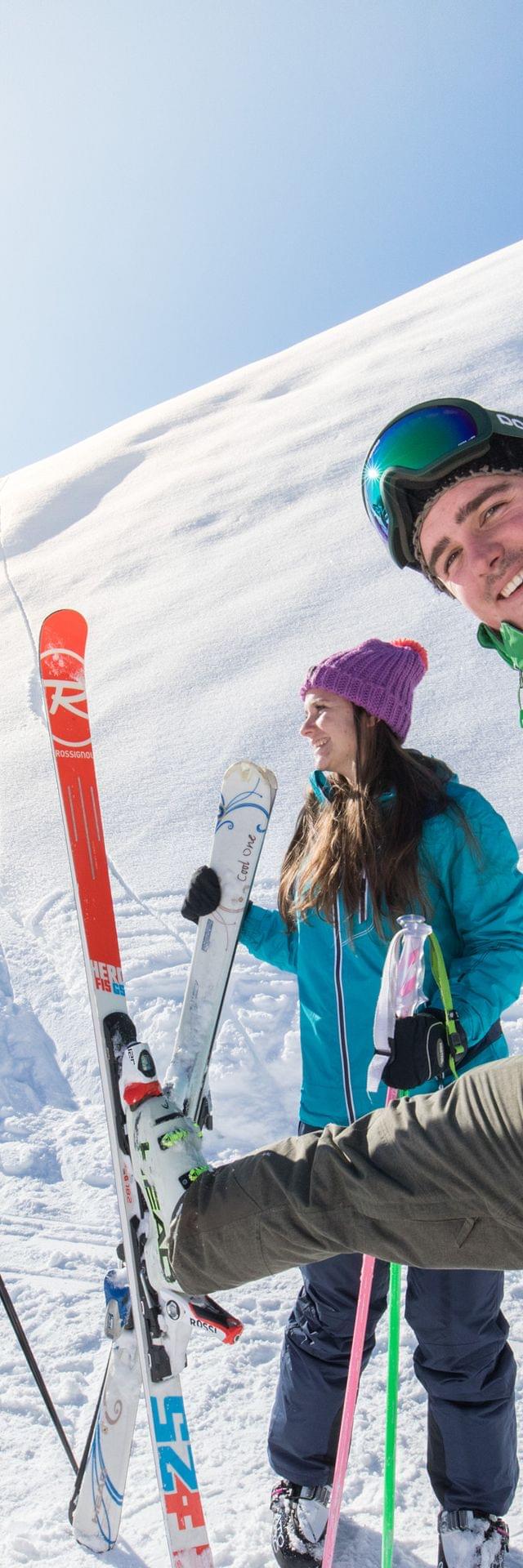Group of skiers smiling on snowy mountain slope in bright winter sun