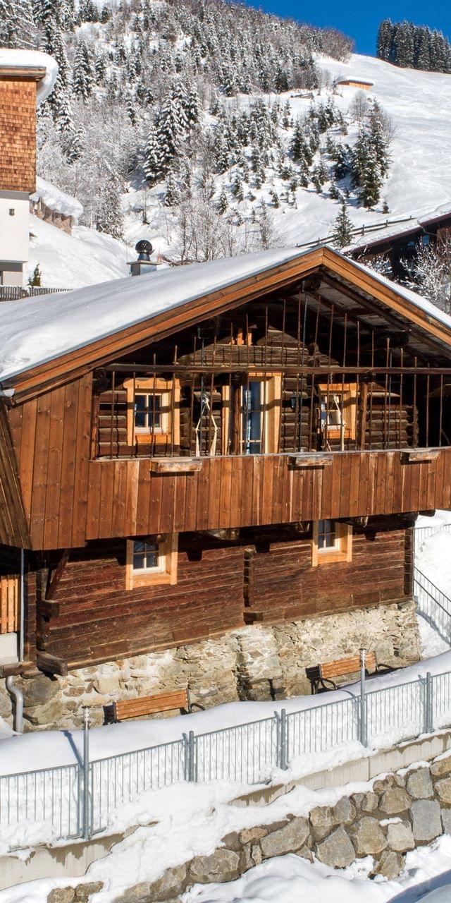 Alpines Holzchalet in verschneiter Berglandschaft nahe Skipisten und Nadelwald