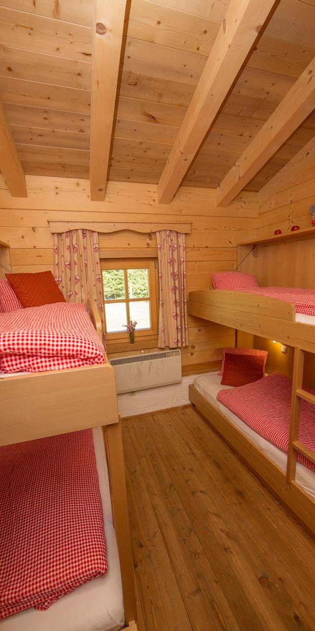 Cozy alpine cabin bedroom with wooden bunk beds and red checkered bedding