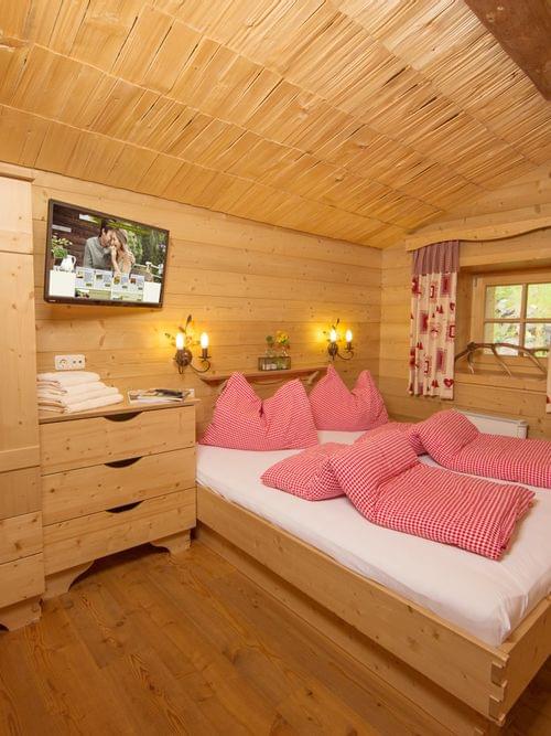 Gemütliches Chalet-Schlafzimmer aus Holz mit rot kariertem Bettzeug und rustikalen Möbeln