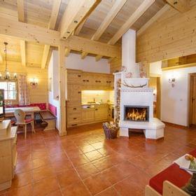 Cozy alpine chalet interior with wooden furnishings, fireplace, and open kitchen