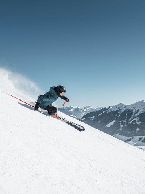 Skier carving down snowy mountain slope on a sunny day in the Alps