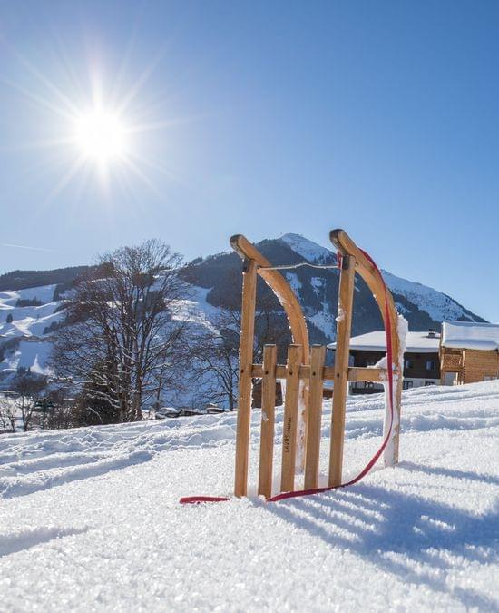 Wooden sled on snowy slope with alpine chalets and sunlit mountain scenery