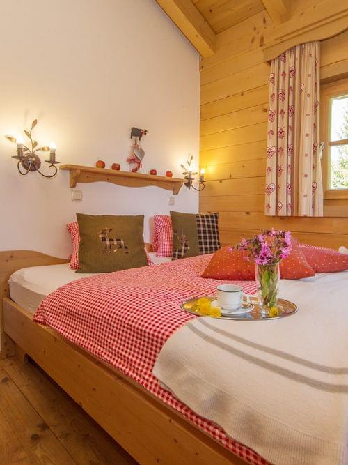 Cozy alpine bedroom with wooden interior, red checkered bedding, and mountain decor