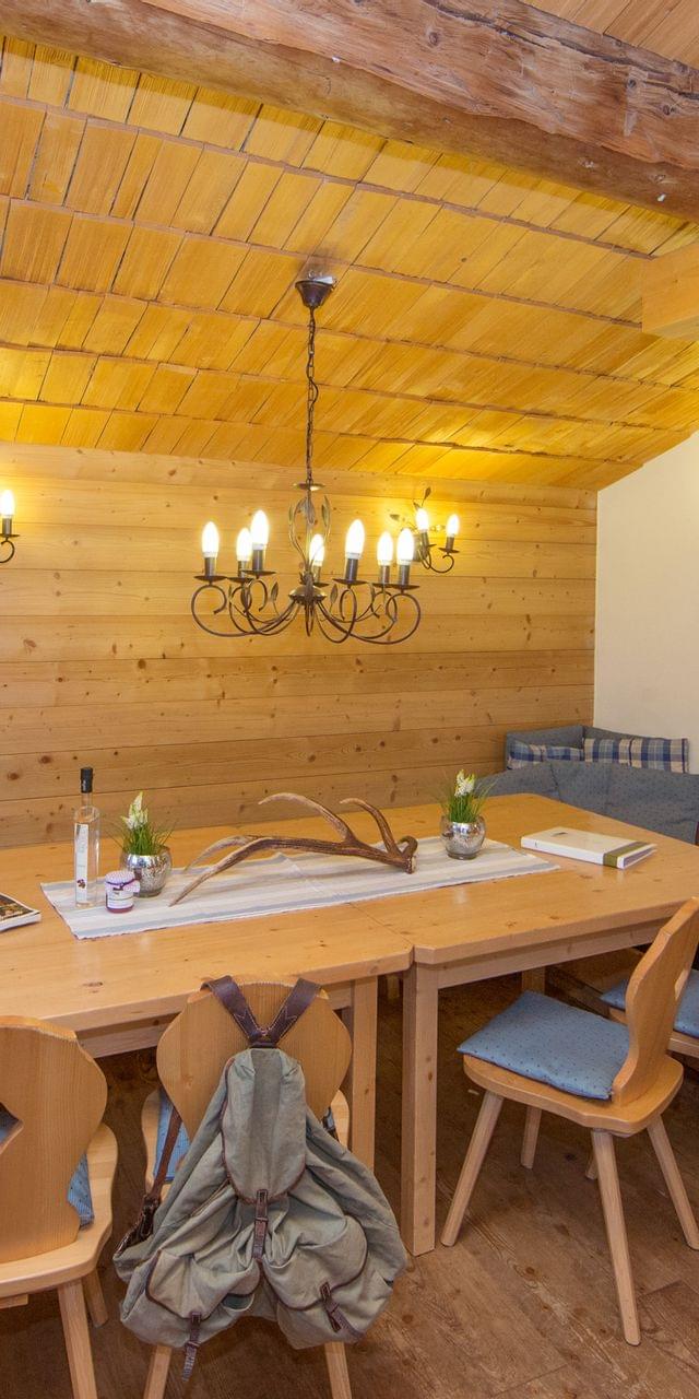Gemütliches alpines Esszimmer aus Holz mit Kronleuchter, rustikalen Möbeln und angrenzendem Schlafzimmer