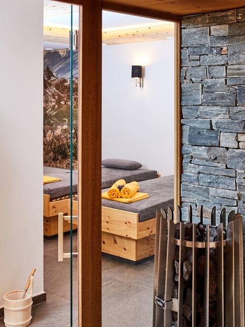 Moderne Spa-Sauna mit Steinwand, Holzliegen, Bademänteln und gerollten Handtüchern