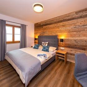 Modernes Hotelzimmer mit Doppelbett, Holzakzentwand und Flachbildfernseher