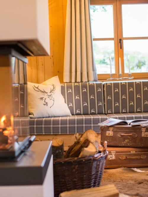 Cozy alpine living room with fireplace, wood accents, plaid sofa and vintage suitcases