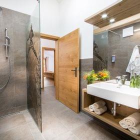 Modernes Hotelbad mit begehbarer Dusche, Holzakzenten und frischen Handtüchern