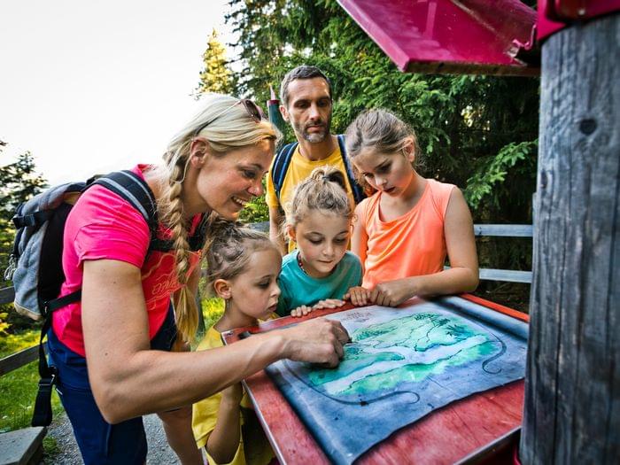 Familie mit Kindern liest im Sommer eine Wanderkarte im Wald