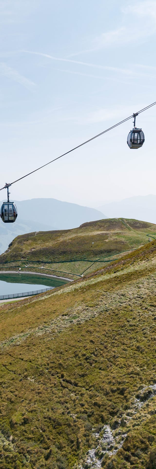 A gondola lift in autumn, with far-reaching views of the surrounding mountains of the region.