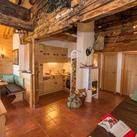 Gemütliches Almhütten-Interieur mit Holzmöbeln, Kachelofen und rustikaler Küche