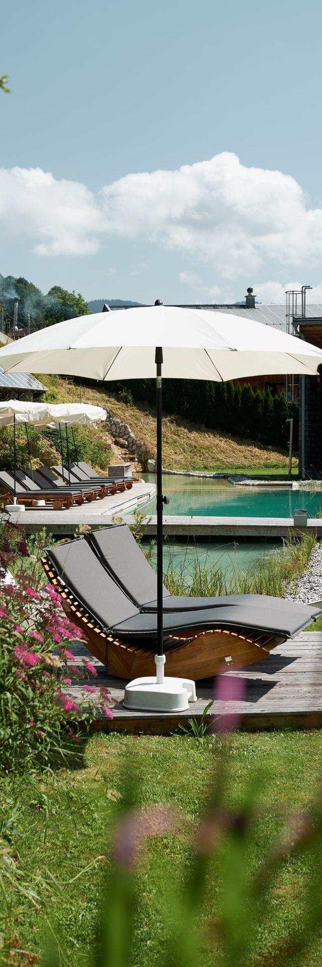 A view of the greenery and the swimming pond, with sun umbrellas and loungers.
