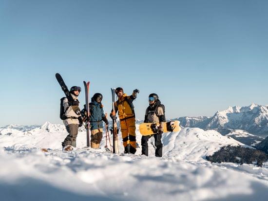 Eine Gruppe von Skifahrern am Berg, die in Richtung der Gipfel deutet 