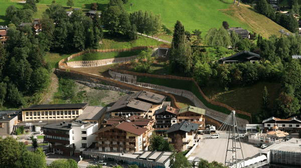 Alpendorf mit modernen Gebäuden, umgeben von grünen Hügeln und Wald