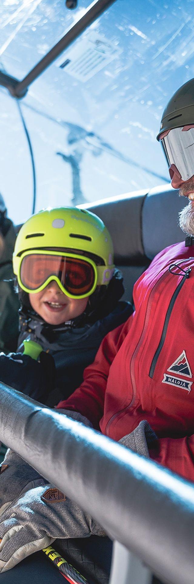 Family in ski gear riding a ski lift on a sunny winter day in the mountains