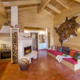 Gemütliches Chalet mit Holzwänden, Kamin, offener Küche und eingebautem Sofa mit bunten Kissen
