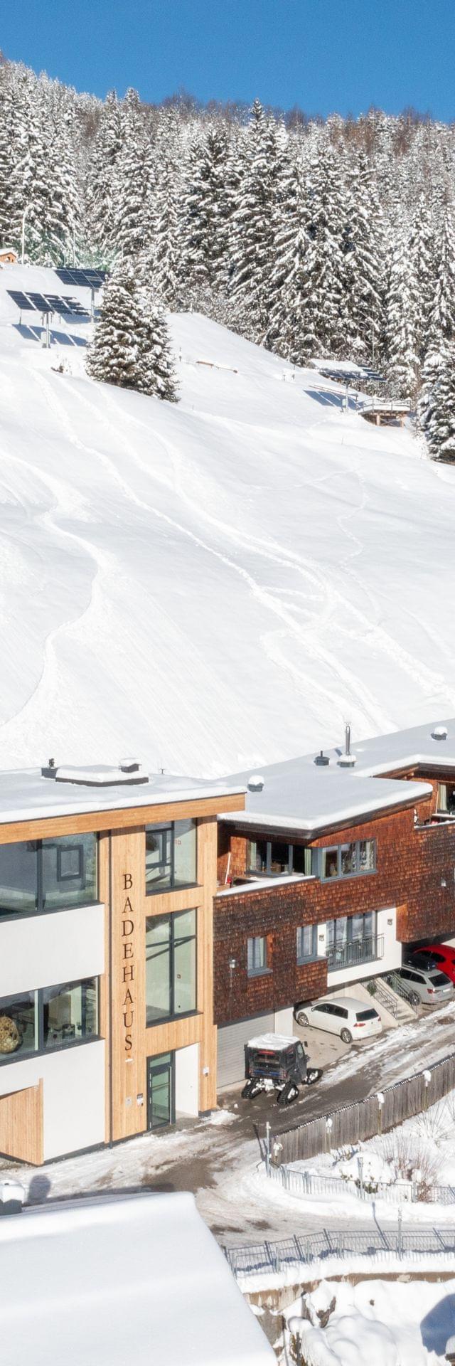 A bird’s-eye view of Bachgut, with wintery mountains and the chalets, including the bathhouse and infinity pool.