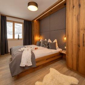 Cozy alpine hotel bedroom with wood furniture, double bed, and mountain view