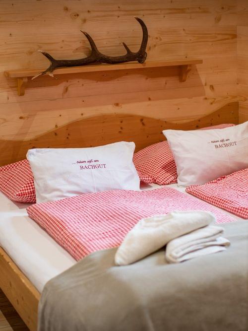 Gemütliches Alpenzimmer mit rot kariertem Bettzeug und Holzverkleidung