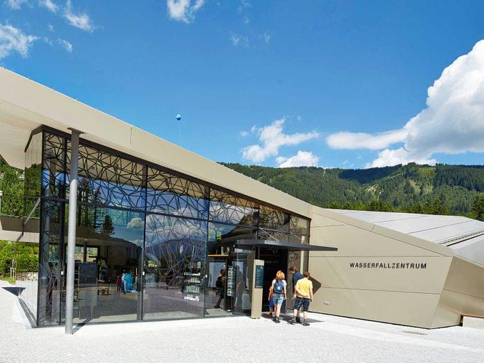 Modern building of the Wasserfallzentrum visitor center with glass facade in alpine setting