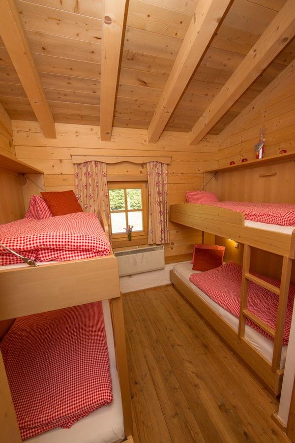 Cozy alpine cabin bedroom with wooden bunk beds and red checkered bedding
