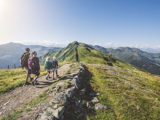 Familie beim Wandern im Hintergrund Berge und Sonnenschein 