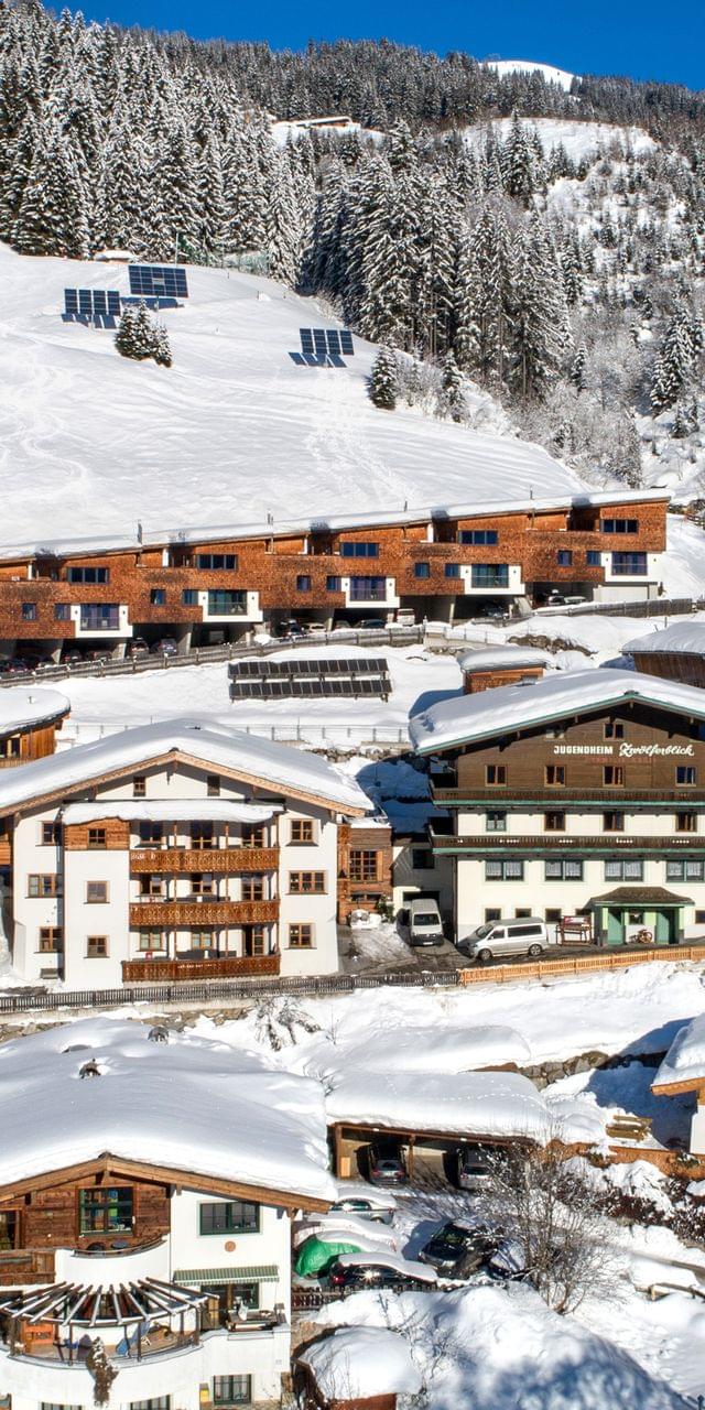 Alpines Skidorf mit Holzhütten und verschneiten Pisten im Winter